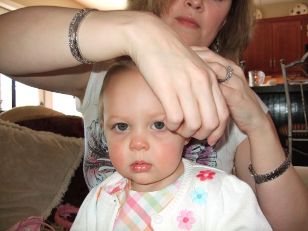 reluctantly letting mommy fix her hair
